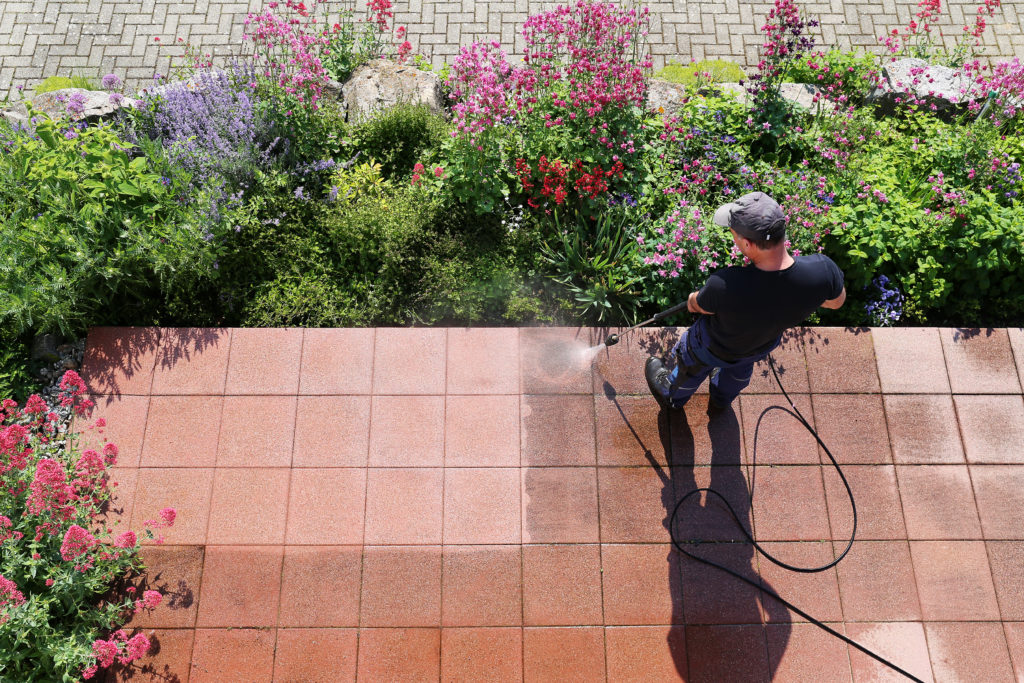 Man pressure washing outside of home